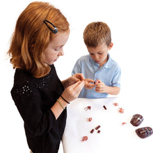 Load image into Gallery viewer, TEDCO Toy Gross Insect 3D Interlocking Blocks Puzzle of red centipede being assembled by a young girl wearing black and boy wearing blue on white table with white background.
