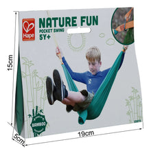Load image into Gallery viewer, Hape bamboo made green and yellow Nature Fun Pocket Hammock Swing with young boy in blue swinging on hammock photo and clip photo on the 15 cm H x 19 cm W x 5 cm D white packaging with green text and graphics against white background.
