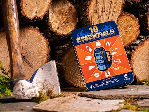 Education Outdoors 10 Essentials Game with blue backpack graphic on orange background and circled by white icons against lumber wood and ax on a stone ground.